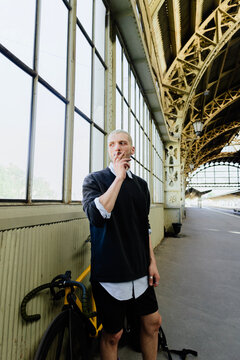 Portrait Of smoking Man With Bicycle At Train Station