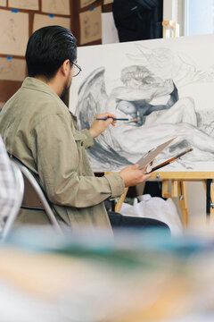 Man sitting and doing a painting.