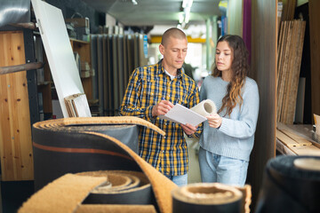 Young positive woman and man discussing shopping list in building materials store