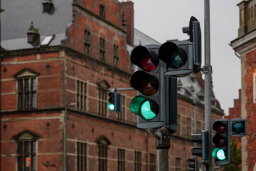 Selective focus at traffic green light and blur background of old classic european style brick building during raining day.