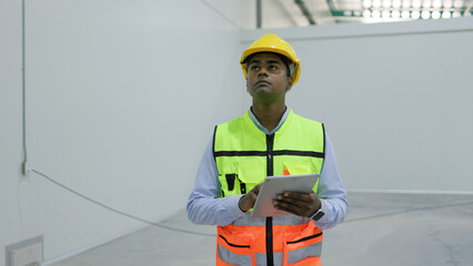 portrait young asian male worker using a digital tablet to check warehouse shelves in a warehouse.