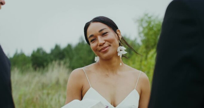Outdoor wedding, close-up of a smiling bride and the Bible in the priest's hands