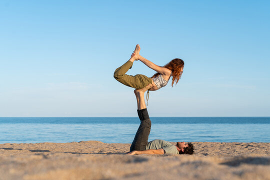 Couple practicing acroyoga at beach