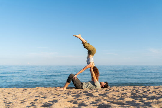 Couple practicing acroyoga at beach