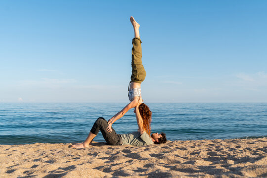 Couple practicing acroyoga at beach