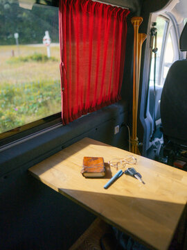 A pen, a notebook, glasses and keys on the table in camper van 