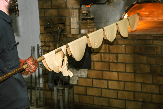 Jewish Man Placing Matzah in Hot Oven.