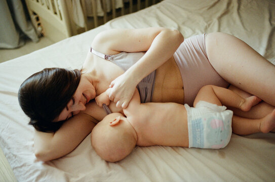 Mother breastfeeding her infant on the bed