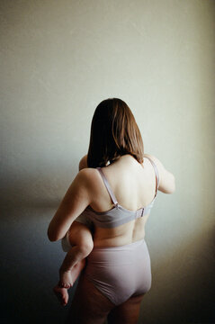 Woman breastfeeding infant standing with back to the camera