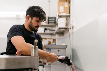 Focused man using casing while making sausage