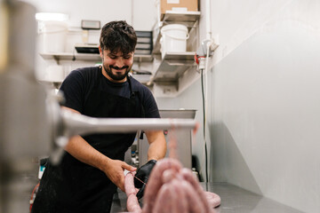 Serious man making sausages with professional equipment