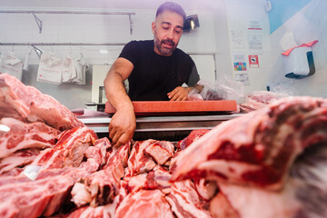 Male butcher taking raw meat from fridge