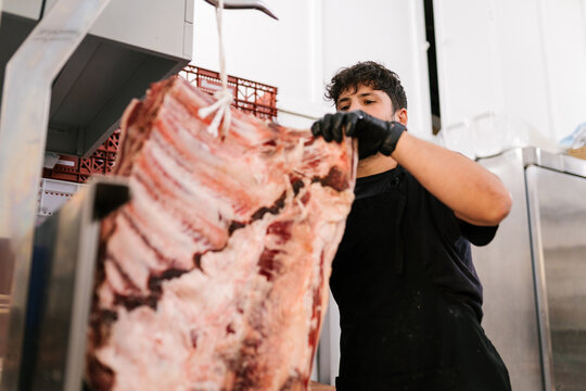 Man cutting fresh beef in butchery shop