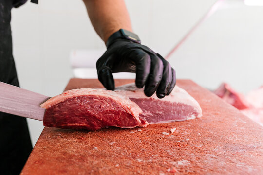 Crop worker cutting raw meat on chopping board