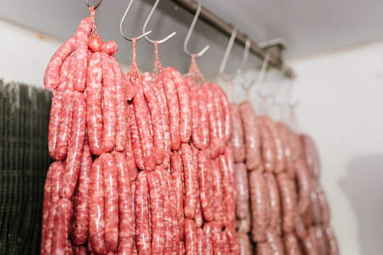Row of fresh sausages hanging on hooks in store