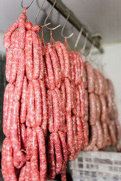 Assorted raw sausages hanging on rack in market