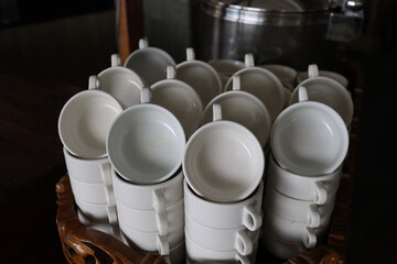 Stacked empty teacups with teaspoons at a function over white background