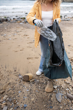 Volunteer collecting garbage from beach.