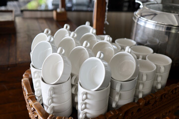 Stacked empty teacups with teaspoons at a function over white background