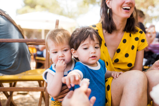 Feeding cute bold babies at summer picnic