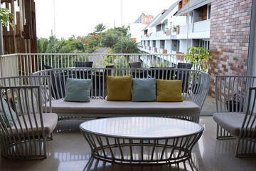 The balcony is decorated elegantly and comfortably with colorful rattan outdoor furniture, bright pillows in soft pastel colors