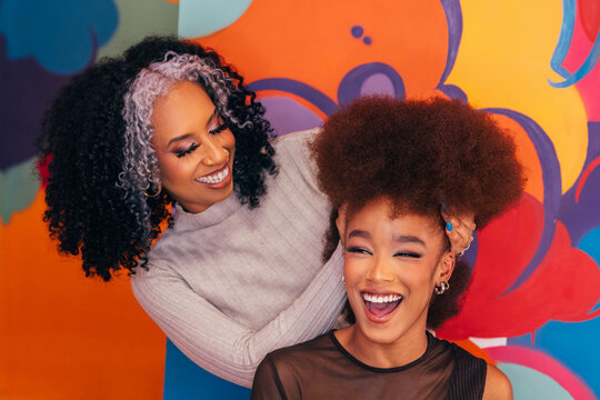Happy hairdresser working on afro hair in hair salon