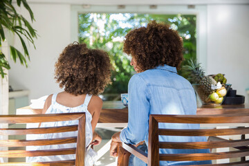 Mother talking with daughter while sitting together at dining table