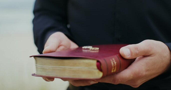 Wedding rings lie on the bible in the priest's hands