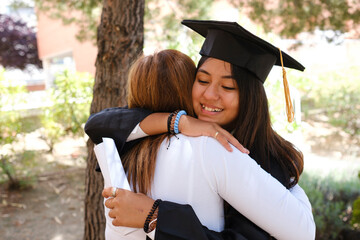 Teenage girl hugging her mother in graduation day