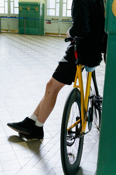 Closeup of man&rsquo;s legs standing inform of yellow bicycle
