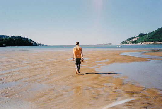 man walking alone on the sandy beach shore