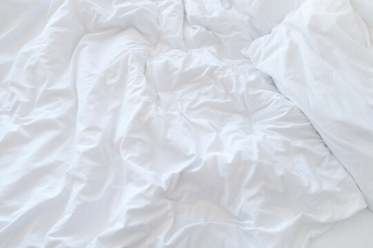 white wrinkled bed sheet and pillow