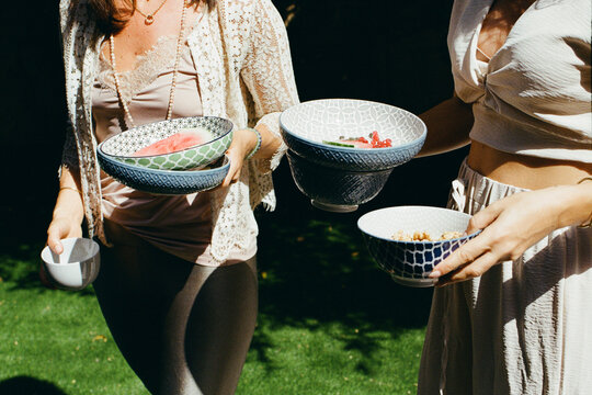 Women with bowls of food in the garden