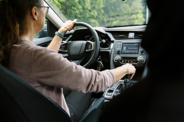 middle aged woman in car putting the vehicle into gear to drive