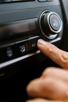 middle aged woman inside a car pushing button