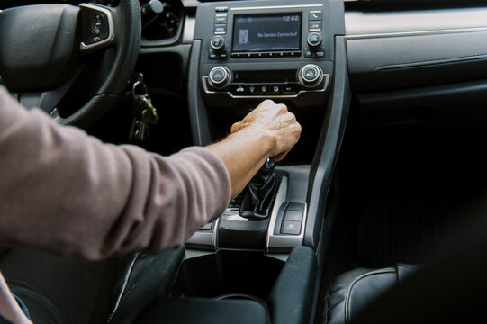 middle aged woman in car putting the vehicle into gear to drive