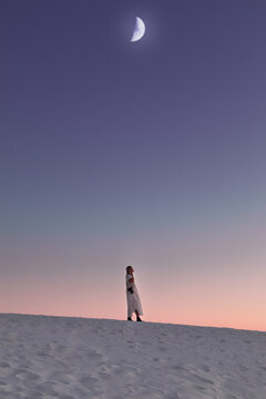 Woman in the desert under a dramatic moon