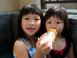 Asian little girl feeds her sister to drink milk
