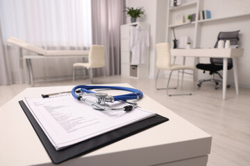 Clipboard and stethoscope on white table in clinic, space for text. Doctor's workplace