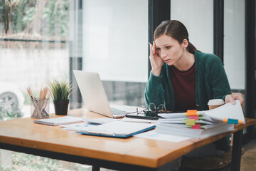 Overworked businesswoman suffering from headache and thinking how to end work.