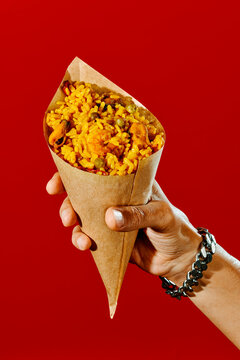 man has a paper cone with paella in his hand