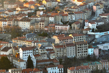 Fototapeta na wymiar Aerial view of dense historic center of Thiers town in Puy-de-Dome department, Auvergne-Rhone-Alpes region in France. Rooftops of old buildings and narrow streets at sunset