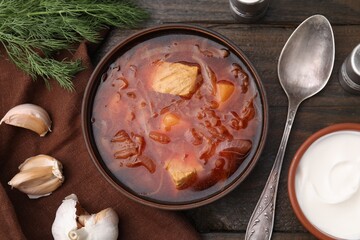 Delicious borscht, garlic and sour cream on wooden table, flat lay