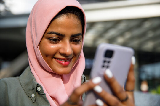 Happy arabic woman text messaging using mobile phone