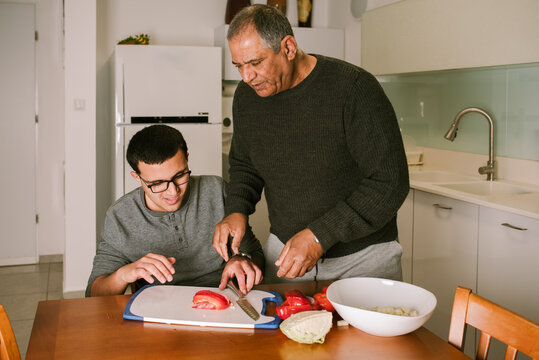 Grandpa 60s Guides a Teenager in Vegetable Cutting.