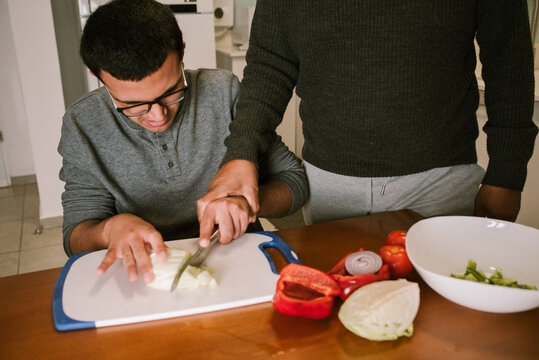 Grandpa 60s Guides a Teenager in Vegetable Cutting.