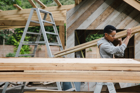 Carpenter stacking wood pile of 2X4 lumber.