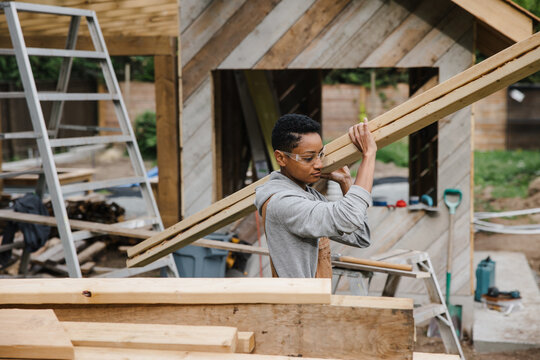 Carpenter stacking wood pile of 2X4 lumber.