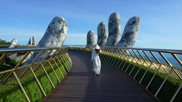 4k slow motion,Asian woman wearing white.Vietnamese culture with traditional conical hat with on the Golden hand Bridge, Da Nang City, Vietnam.