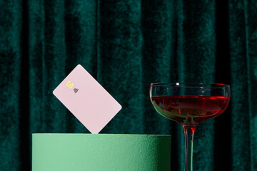 Glass of wine on cubes podium with credit cards over green